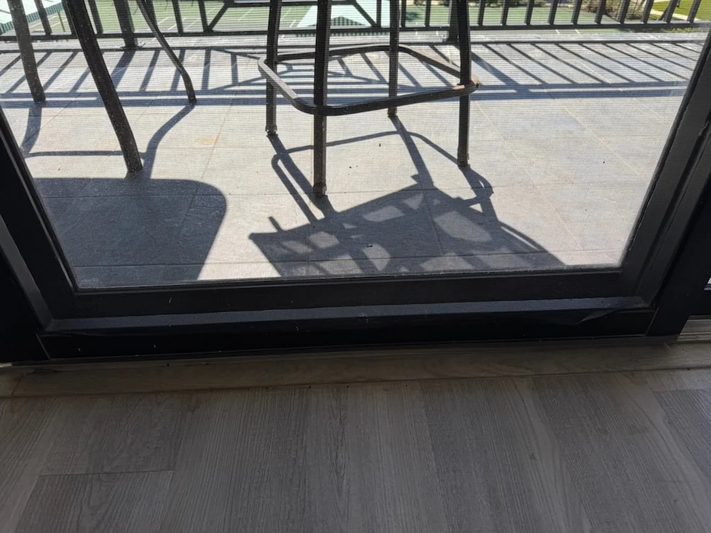 The lower frame and threshold of a balcony sliding door, viewed from inside.