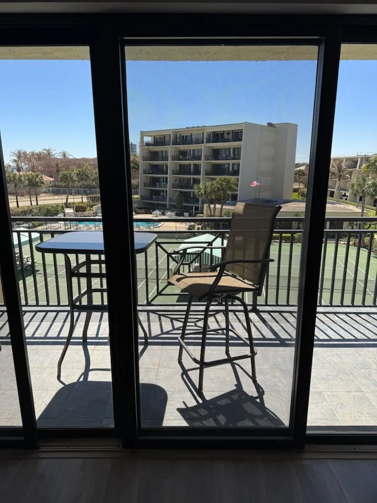 A dark-framed sliding glass door opening onto a furnished balcony.