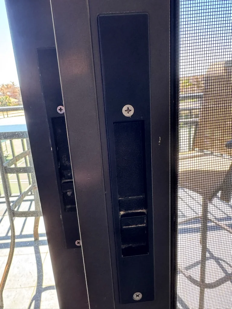 Close-up of the latch and hardware in a dark sliding door frame.