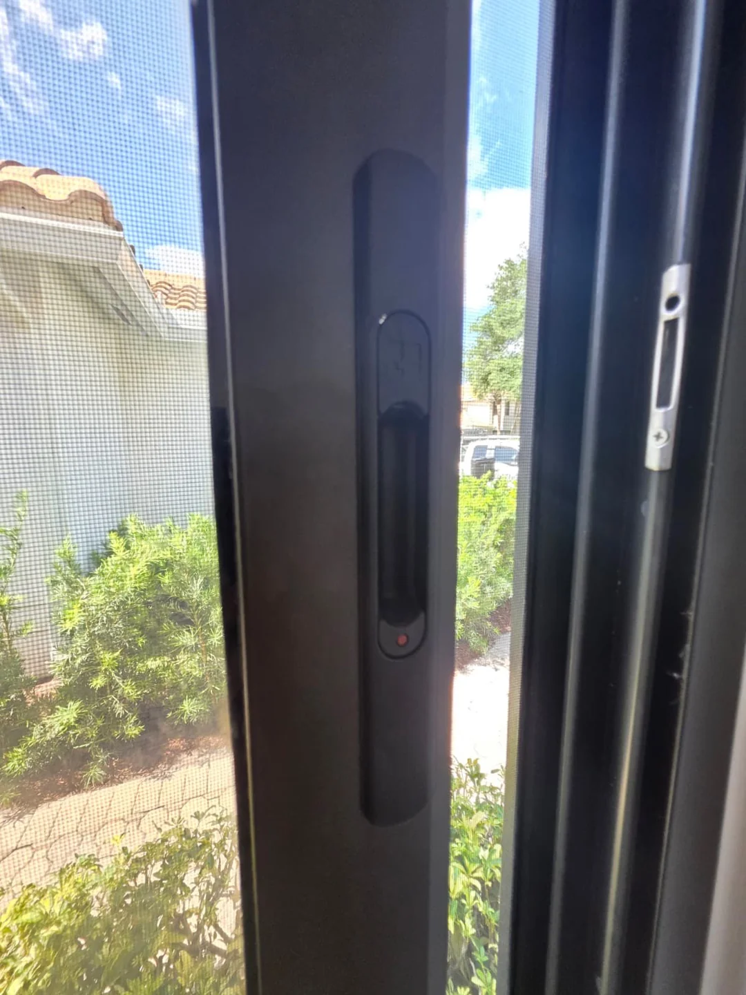 A recessed handle and adjoining frame on a dark sliding door.