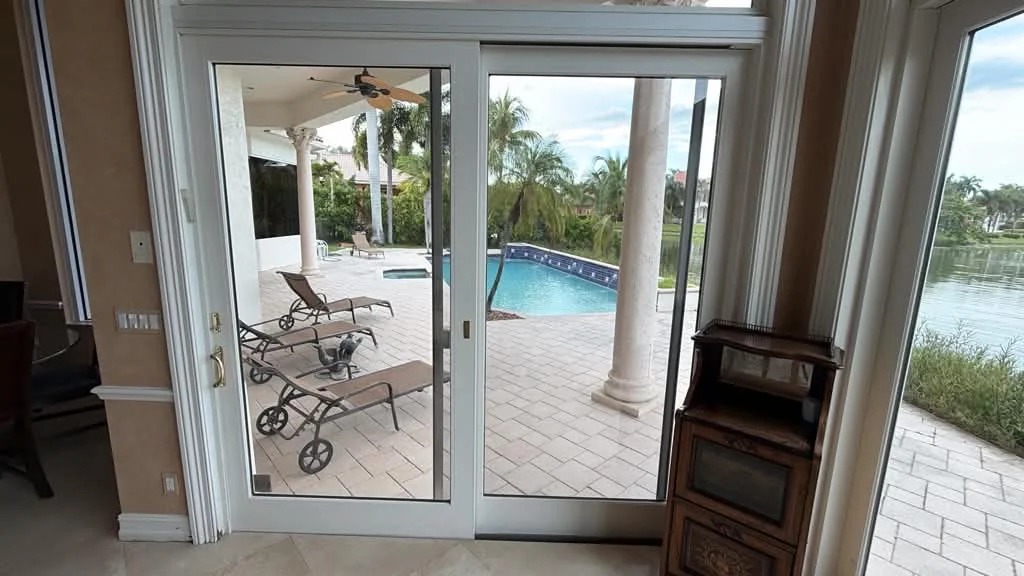 A white-framed glass patio door viewed from a room toward the pool area.