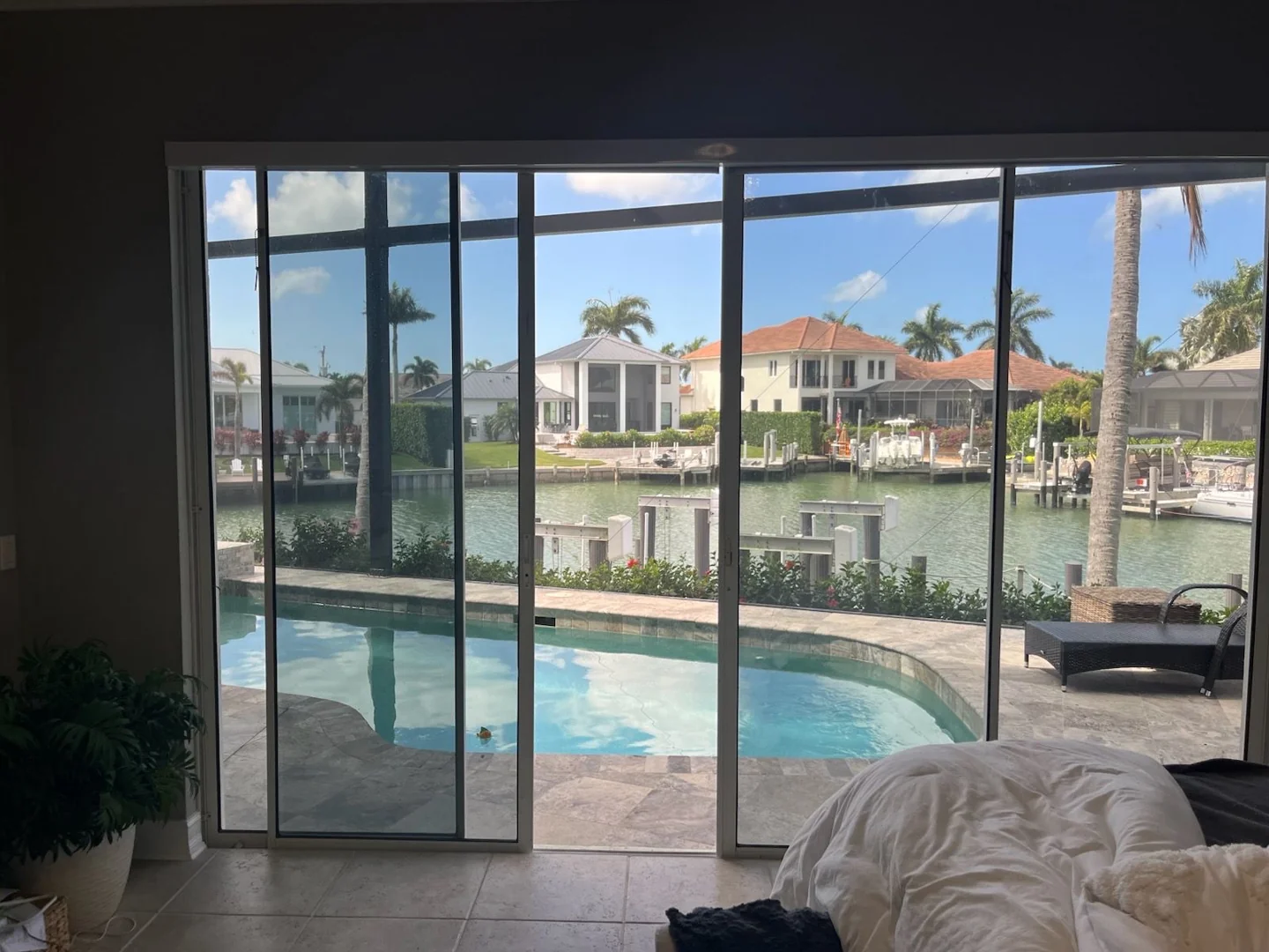 A wide glass door opening overlooking a screened pool and waterway.