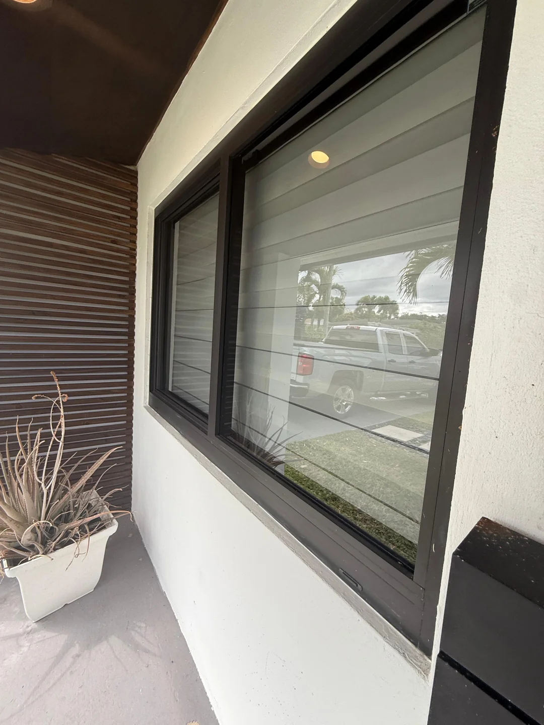 A wide dark-framed window beneath a covered exterior walkway.